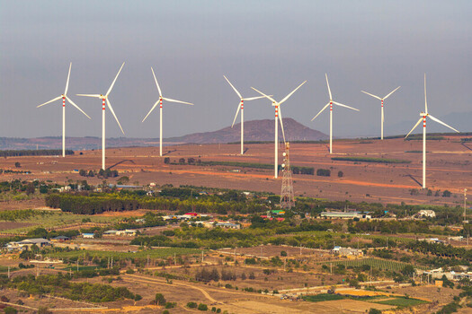 Aerial view of the Phuoc Dinh Wind Farm with large white wind turbines standing in a dry landscape with sparse vegetation and rolling hills in the background in Phuoc Dinh Ninh Thuan Vietnam. Aerial view of the Phuoc Dinh Wind Farm with large white wind turbines standing in a dry landscape with sparse vegetation and rolling hills in the background in Phuoc Dinh Ninh Thuan Vietnam.