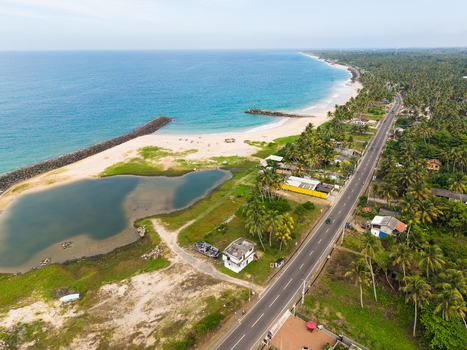 Aerial view of the scenic coastline with a coastal road sandy beach and turquoise ocean waters near Peraliya Southern Province Sri Lanka. Aerial view of the scenic coastline with a coastal road sandy beach and turquoise ocean waters near Peraliya Southern Province Sri Lanka.