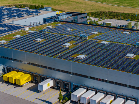 Aerial view of Logistikzentrum Allhaming featuring a large industrial building with extensive rooftop solar panels and loading docks with trailers in Allhaming Oberosterreich Austria. Aerial view of Logistikzentrum Allhaming featuring a large industrial building with extensive rooftop solar panels and loading docks with trailers in Allhaming Oberosterreich Austria.