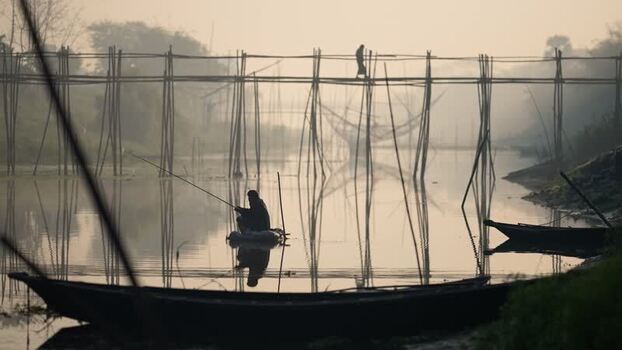 View of a person walking on a bamboo bridge in Bogura Bangladesh. View of a person walking on a bamboo bridge in Bogura Bangladesh.
