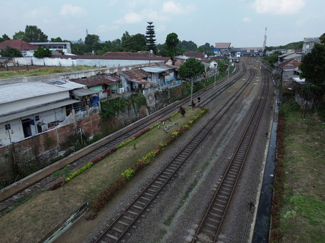 Aerial view of Stasiun Malang Kota Baru with railway tracks surrounding residential buildings and lush greenery in Kecamatan Klojen Jawa Timur Indonesia.