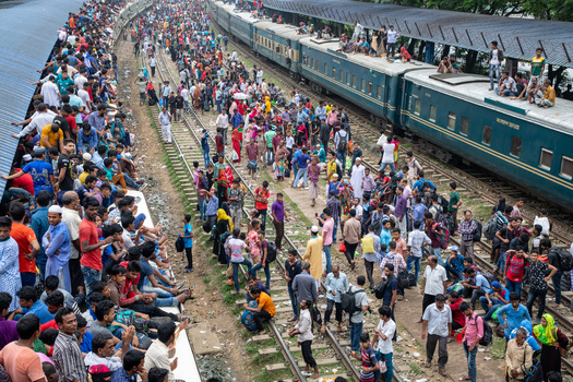 Dhaka Bangladesh 15 June 2018 View of the crowded Airport Railway Station with thousands of passengers waiting on platforms and tracks some sitting on top of green train carriages. Dhaka Bangladesh 15 June 2018 View of the crowded Airport Railway Station with thousands of passengers waiting on platforms and tracks some sitting on top of green train carriages.