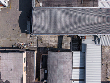 Aerial view of industrial buildings with corrugated metal roofs and concrete courtyards in an urban setting in Casale Monferrato Piedmont Italy. Aerial view of industrial buildings with corrugated metal roofs and concrete courtyards in an urban setting in Casale Monferrato Piedmont Italy.