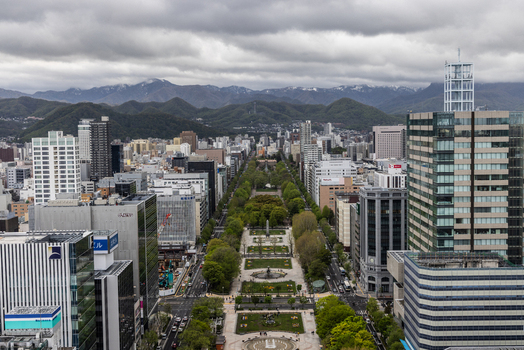 Aerial view of Odori Park surrounded by modern skyscrapers and lush greenery with mountains in the background in Sapporo Hokkaido Japan. Aerial view of Odori Park surrounded by modern skyscrapers and lush greenery with mountains in the background in Sapporo Hokkaido Japan.