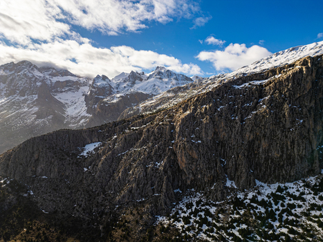 Aerial view of Aladaglar National Park featuring rugged mountain peaks snow covered slopes rocky cliffs and scattered evergreen trees in Demirkazik Nigde Turkiye. Aerial view of Aladaglar National Park featuring rugged mountain peaks snow covered slopes rocky cliffs and scattered evergreen trees in Demirkazik Nigde Turkiye.