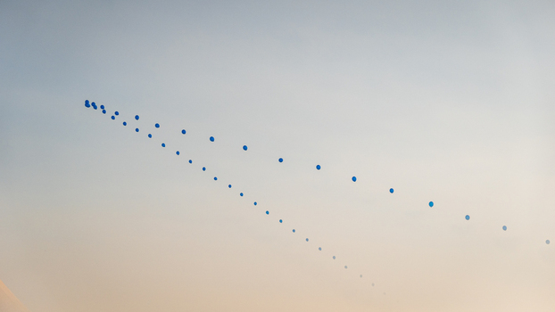 View of a line of blue balloons floating in the clear sky over Switzerland.