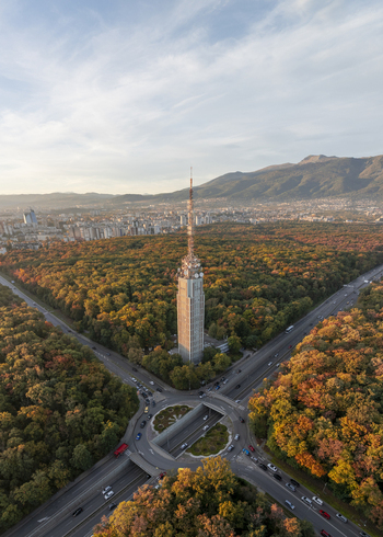 Aerial view of the Sofia TV Tower surrounded by vibrant autumn forest with a road intersection and tunnel in the foreground and city skyline in Sofia Sofia City Province Bulgaria. Aerial view of the Sofia TV Tower surrounded by vibrant autumn forest with a road intersection and tunnel in the foreground and city skyline in Sofia Sofia City Province Bulgaria.