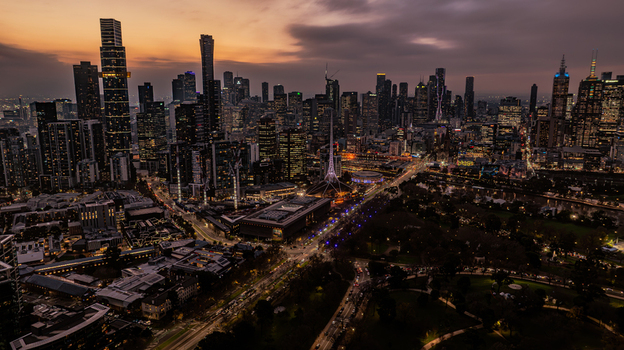 Aerial view of the Melbourne skyline at dusk with illuminated skyscrapers the Arts Centre spire and city lights reflecting over the urban landscape in Southbank Victoria Australia. Aerial view of the Melbourne skyline at dusk with illuminated skyscrapers the Arts Centre spire and city lights reflecting over the urban landscape in Southbank Victoria Australia.