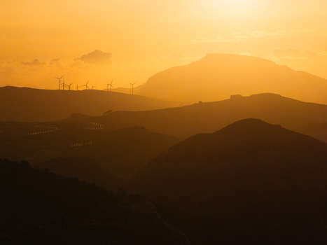 Aerial view of the Riserva Naturale Orientata dello Zingaro at sunset with wind turbines silhouetted against the golden sky over rolling hills in San Vito Lo Capo Sicilia Italy. Aerial view of the Riserva Naturale Orientata dello Zingaro at sunset with wind turbines silhouetted against the golden sky over rolling hills in San Vito Lo Capo Sicilia Italy.