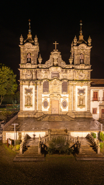 Aerial view of the illuminated Church Santa Marinha Da Costa with its ornate stone facade and twin bell towers at night in Costa Guimaraes Portugal.