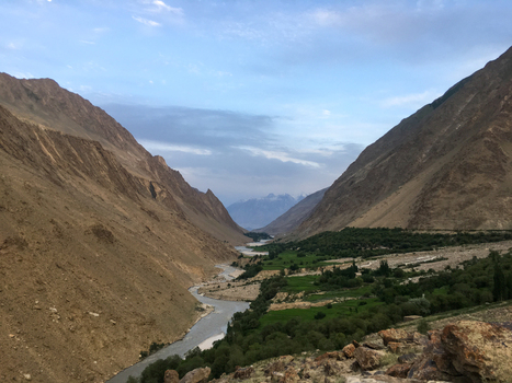 View of Hushe River Valley with a winding river flowing through the lush green valley floor surrounded by towering arid mountains under a soft sky in Saling Gilgit Pakistan. View of Hushe River Valley with a winding river flowing through the lush green valley floor surrounded by towering arid mountains under a soft sky in Saling Gilgit Pakistan.