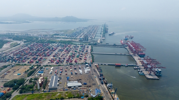 Aerial view of Jawaharlal Nehru Port Authority with container terminals stacked shipping containers cargo ships at piers and industrial infrastructure in Juna Sheva Maharashtra India. Aerial view of Jawaharlal Nehru Port Authority with container terminals stacked shipping containers cargo ships at piers and industrial infrastructure in Juna Sheva Maharashtra India.