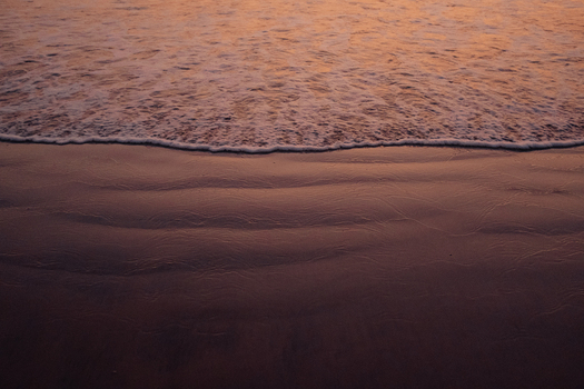 View of gentle waves caress the dark sandy shore under the warm glow of twilight creating a serene coastal scene Chiplun Maharashtra India. View of gentle waves caress the dark sandy shore under the warm glow of twilight creating a serene coastal scene Chiplun Maharashtra India.