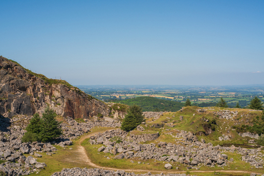 View of the Cheesewring granite rock formation rugged terrain rocky slopes and green valley landscape under a clear blue sky in Minions Cornwall United Kingdom. View of the Cheesewring granite rock formation rugged terrain rocky slopes and green valley landscape under a clear blue sky in Minions Cornwall United Kingdom.