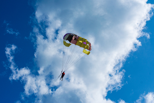 Cox s Bazar Bangladesh 18 August 2023 Aerial view of a vibrant parasailor suspended against a backdrop of fluffy white clouds and a deep blue sky. Cox s Bazar Bangladesh 18 August 2023 Aerial view of a vibrant parasailor suspended against a backdrop of fluffy white clouds and a deep blue sky.