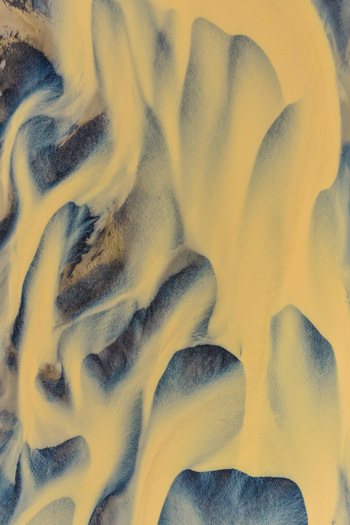 Aerial view of the braided glacial river patterns flowing from Drangajokull with intricate sediment channels and dark volcanic terrain in Isafjordur Isafjardarbaer Iceland. Aerial view of the braided glacial river patterns flowing from Drangajokull with intricate sediment channels and dark volcanic terrain in Isafjordur Isafjardarbaer Iceland.