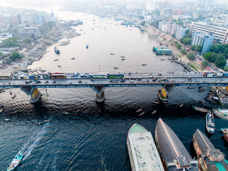 Aerial view of Sadarghat on the Buriganga River with numerous boats a busy bridge with traffic and urban buildings along the riverbanks in Dhaka Dhaka Division Bangladesh. Aerial view of Sadarghat on the Buriganga River with numerous boats a busy bridge with traffic and urban buildings along the riverbanks in Dhaka Dhaka Division Bangladesh.