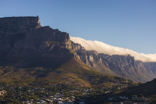 View of Table Mountain s imposing silhouette meets a river of clouds casting shadows over the city below a stunning display of nature s grandeur Cape Town Western Cape South Africa.