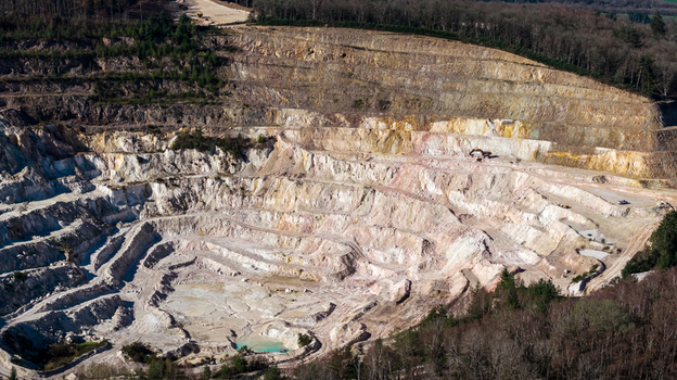 Aerial view of a stark quarry s tiered landscape where raw earth meets encroaching forest &Eacute;chassi&egrave;res Auvergne Rh&ocirc;ne Alpes France.