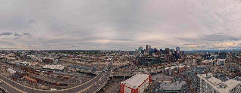 Aerial view of the Denver skyline featuring the Coors Field stadium extensive railway tracks and highway interchanges under a cloudy sky in Denver Colorado United States. Aerial view of the Denver skyline featuring the Coors Field stadium extensive railway tracks and highway interchanges under a cloudy sky in Denver Colorado United States.