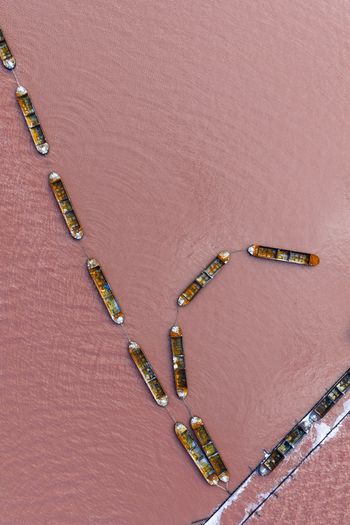 Aerial view of cargo ships sailing through the pink waters of Las Salinas creating a striking contrast of colors and textures San Pedro del Pinatar Region of Murcia Spain. Aerial view of cargo ships sailing through the pink waters of Las Salinas creating a striking contrast of colors and textures San Pedro del Pinatar Region of Murcia Spain.