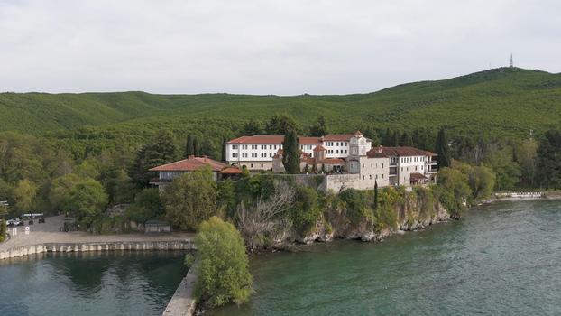 Aerial view of Saint Naum Monastery situated on a rocky cliff overlooking the waters of Lake Ohrid surrounded by lush green hills in Municipality of Ohrid North Macedonia.