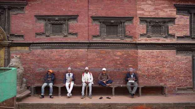 View of men sitting by a historic brick wall in Kathmandu Nepal.
