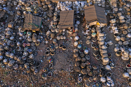 Aerial view of numerous sacks filled with plastic waste and recycling materials arranged in rows with makeshift shelters near the Buriganga River in Dhaka Dhaka Division Bangladesh. Aerial view of numerous sacks filled with plastic waste and recycling materials arranged in rows with makeshift shelters near the Buriganga River in Dhaka Dhaka Division Bangladesh.