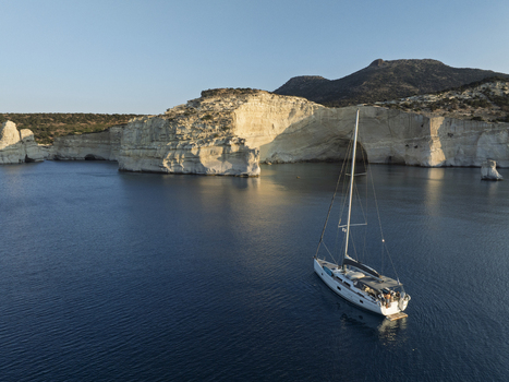 Aerial view of a sailboat anchored in the calm blue waters near the white volcanic cliffs of Sarakiniko beach in Milos Greece. Aerial view of a sailboat anchored in the calm blue waters near the white volcanic cliffs of Sarakiniko beach in Milos Greece.