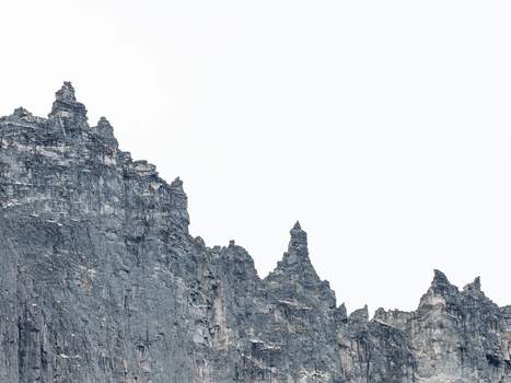 Aerial view of the jagged steep rock faces of the Troll Wall mountain range with sharp peaks and rugged stone textures in Andalsnes More og Romsdal Norway. Aerial view of the jagged steep rock faces of the Troll Wall mountain range with sharp peaks and rugged stone textures in Andalsnes More og Romsdal Norway.
