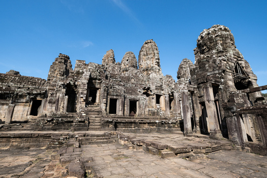 View of the ancient stone towers and intricate carvings of the Bayon Temple under a clear blue sky in Krong Siem Reap Siem Reap Province Cambodia. View of the ancient stone towers and intricate carvings of the Bayon Temple under a clear blue sky in Krong Siem Reap Siem Reap Province Cambodia.