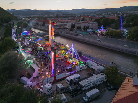 Aerial view of the Radvansky jarmok carnival with illuminated rides and crowds along the river in Banska Bystrica Banskobystricky kraj Slovakia.