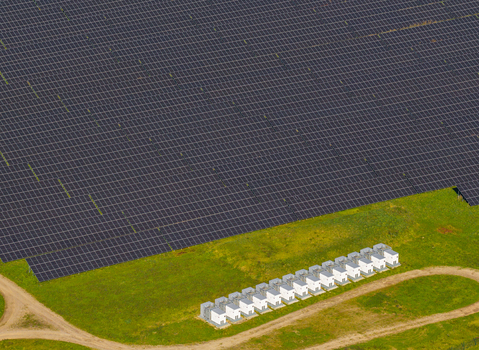 Aerial view of a large solar farm with rows of photovoltaic panels and a line of white electrical inverters situated on a green field in Pomeranian Voivodeshi Poland. Aerial view of a large solar farm with rows of photovoltaic panels and a line of white electrical inverters situated on a green field in Pomeranian Voivodeshi Poland.