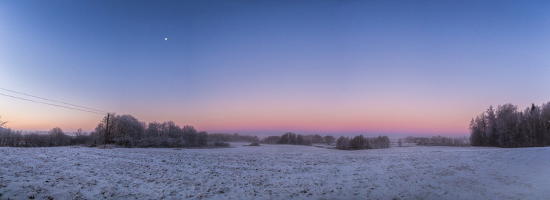 Aerial view of a snow covered landscape with frost dusted trees and a vibrant twilight sky over the fields of Latvia. Aerial view of a snow covered landscape with frost dusted trees and a vibrant twilight sky over the fields of Latvia.