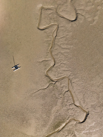 Aerial view of a small boat sailing in Abel Tasman National Park with winding streams of water Abel Tasman Tasman Region New Zealand. Aerial view of a small boat sailing in Abel Tasman National Park with winding streams of water Abel Tasman Tasman Region New Zealand.