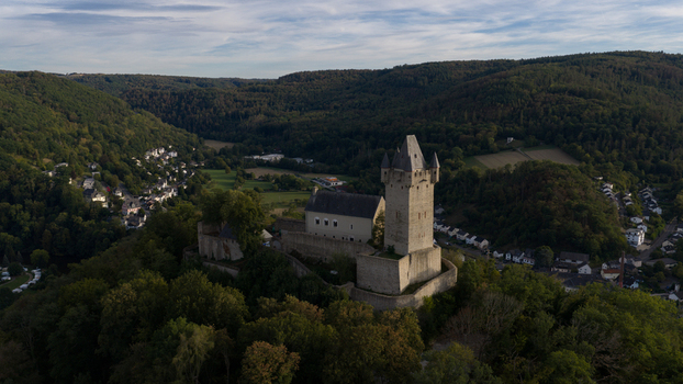 Aerial view of Nassau Castle perched on a forested hill overlooking the town with stone walls a tall tower and lush green valley landscape in Nassau Rheinland Pfalz Germany.