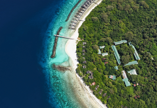 Aerial view of an abandoned island resort with lush green vegetation white sandy beaches and turquoise coral reefs surrounded by deep blue ocean waters in Muraidhoo Haa Alif Atoll Maldives. Aerial view of an abandoned island resort with lush green vegetation white sandy beaches and turquoise coral reefs surrounded by deep blue ocean waters in Muraidhoo Haa Alif Atoll Maldives.