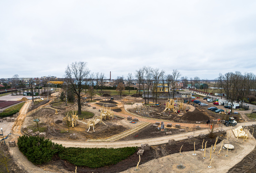 Aerial view of a park under construction featuring wooden play structures dirt paths and scattered trees in Latvia. Aerial view of a park under construction featuring wooden play structures dirt paths and scattered trees in Latvia.