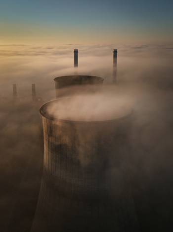 Aerial view of the RWE Clauscentrale power plant cooling towers and chimneys rising above a thick layer of morning fog at sunrise in Maasbracht Limburg Netherlands. Aerial view of the RWE Clauscentrale power plant cooling towers and chimneys rising above a thick layer of morning fog at sunrise in Maasbracht Limburg Netherlands.