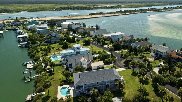 Aerial view of Matanzas Inlet featuring waterfront houses with swimming pools private docks and palm trees along the coastal waterway in St. Johns County Florida United States. Aerial view of Matanzas Inlet featuring waterfront houses with swimming pools private docks and palm trees along the coastal waterway in St. Johns County Florida United States.