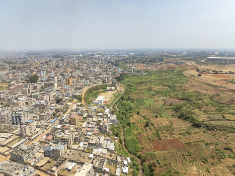 Aerial view of the Lucky Summer neighborhood in Nairobi showing dense residential buildings adjacent to open green fields and agricultural land in Nairobi Nairobi County Kenya. Aerial view of the Lucky Summer neighborhood in Nairobi showing dense residential buildings adjacent to open green fields and agricultural land in Nairobi Nairobi County Kenya.