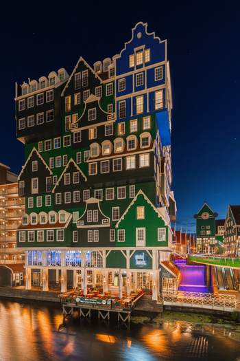 Zaandam Netherlands 10 September 2025 View of Inntel Hotels Amsterdam Zaandam with its unique stacked traditional Dutch house facade illuminated at night by the canal.