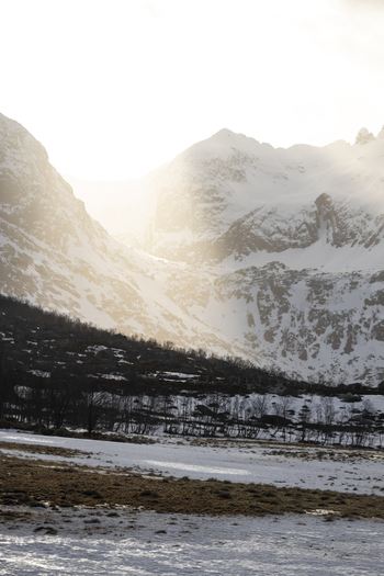 View of snow covered mountain peaks under a bright winter sun with a valley floor in the foreground in Kvaloya Troms Norway. View of snow covered mountain peaks under a bright winter sun with a valley floor in the foreground in Kvaloya Troms Norway.