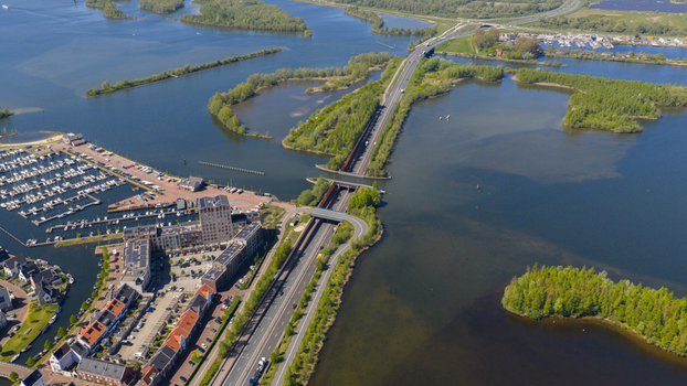 Aerial view of the Aquaduct Veluwemeer with cars driving under the water bridge next to a marina and green islands in Harderwijk Gelderland Netherlands. Aerial view of the Aquaduct Veluwemeer with cars driving under the water bridge next to a marina and green islands in Harderwijk Gelderland Netherlands.