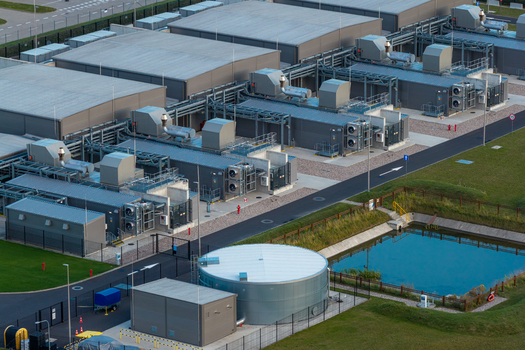 Aerial view of advanced data center facility with industrial buildings cooling units and a water tank in the surrounding green landscape in Warsaw Masovian Voivodeship Poland. Aerial view of advanced data center facility with industrial buildings cooling units and a water tank in the surrounding green landscape in Warsaw Masovian Voivodeship Poland.