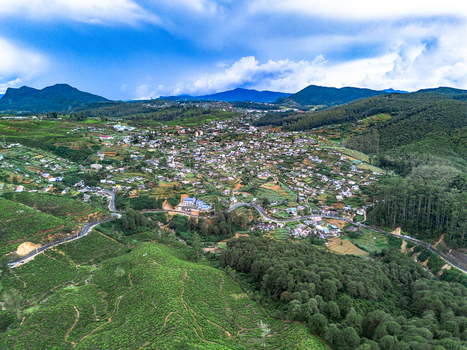 Aerial view of the town of Nuwara Eliya surrounded by lush green tea plantations winding roads and rolling hills in Nuwara Eliya Central Province Sri Lanka. Aerial view of the town of Nuwara Eliya surrounded by lush green tea plantations winding roads and rolling hills in Nuwara Eliya Central Province Sri Lanka.