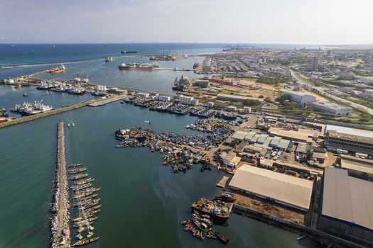 Aerial view of a bustling harbor dotted with ships boats and industrial structures contrasting with the calm blue sea Tema Ghana. Aerial view of a bustling harbor dotted with ships boats and industrial structures contrasting with the calm blue sea Tema Ghana.