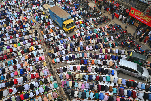 Tongi Dhaka Division Bangladesh 27 July 2026 Aerial view of Tongi Ijtema Maidan with a large crowd of people performing prayer on colorful mats surrounded by vehicles.