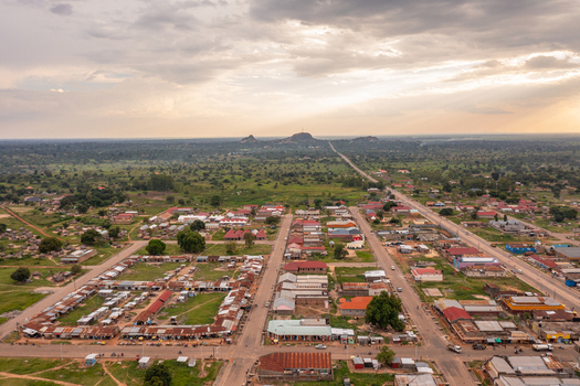 Aerial view of Katakwi Town Council featuring a grid of buildings and market stalls surrounded by lush green plains under a dramatic cloudy sky in Katakwi Eastern Region Uganda. Aerial view of Katakwi Town Council featuring a grid of buildings and market stalls surrounded by lush green plains under a dramatic cloudy sky in Katakwi Eastern Region Uganda.
