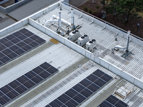 Melbourne VIC Australia 25 September 2026 Aerial view of a corrugated metal rooftop featuring solar panels HVAC units ventilation pipes and a maintenance ladder.